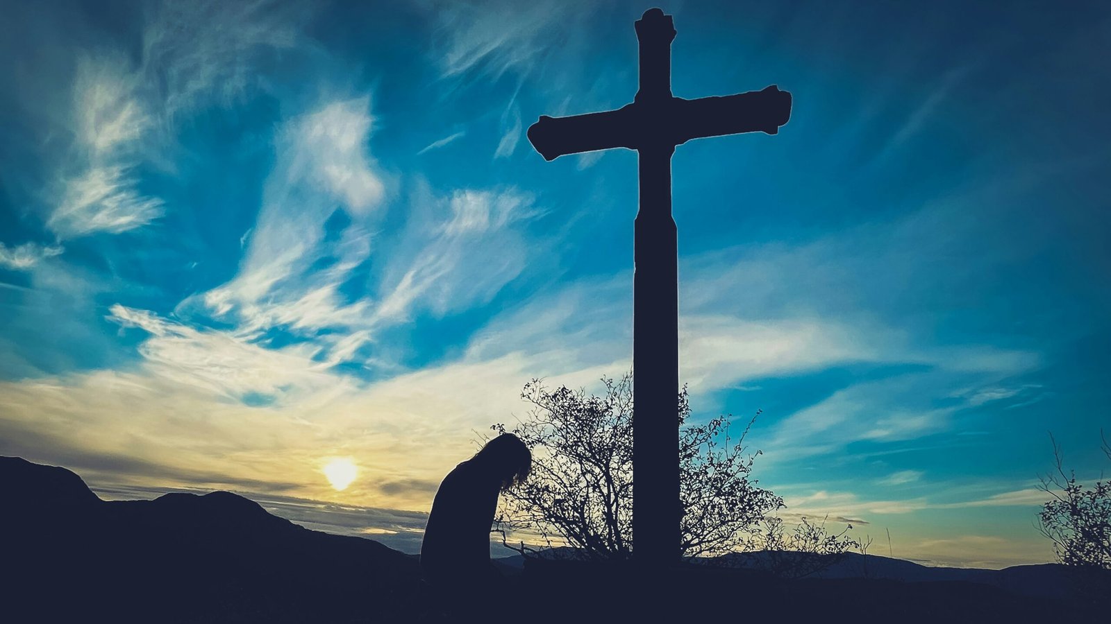 a person kneeling down in front of a cross